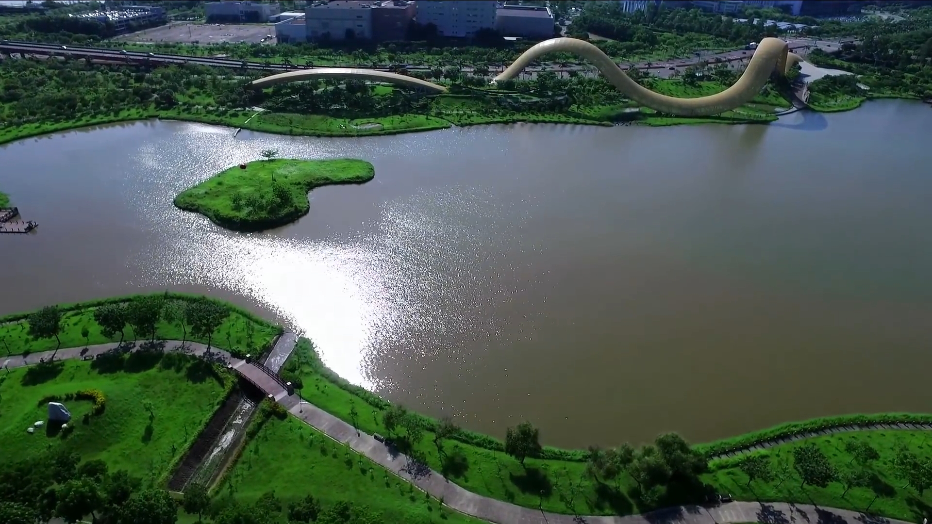 南部科學園區空拍景觀：滯洪池水域與水中綠洲，遠方為湖畔金色波浪造型景觀建築