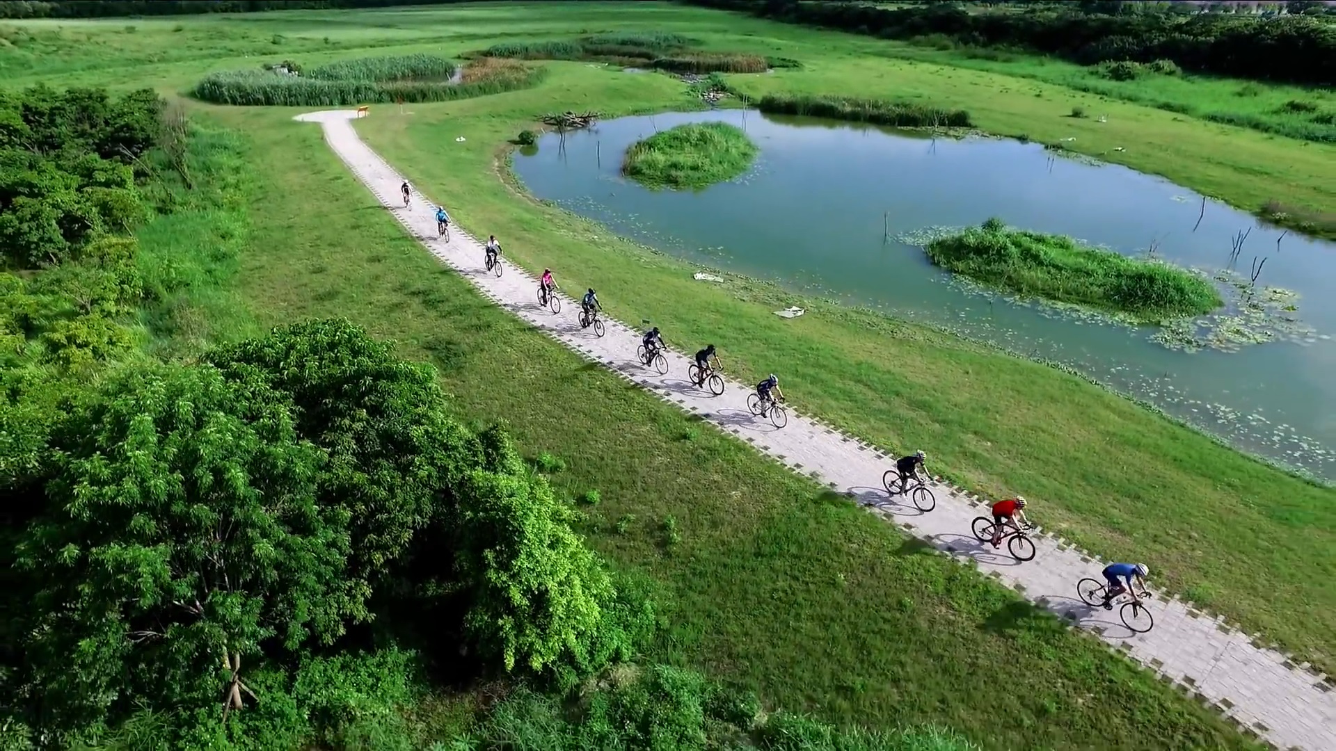 南部科學園區空拍景觀：滯洪生態池畔的自行車道，多位民眾騎乘自行車